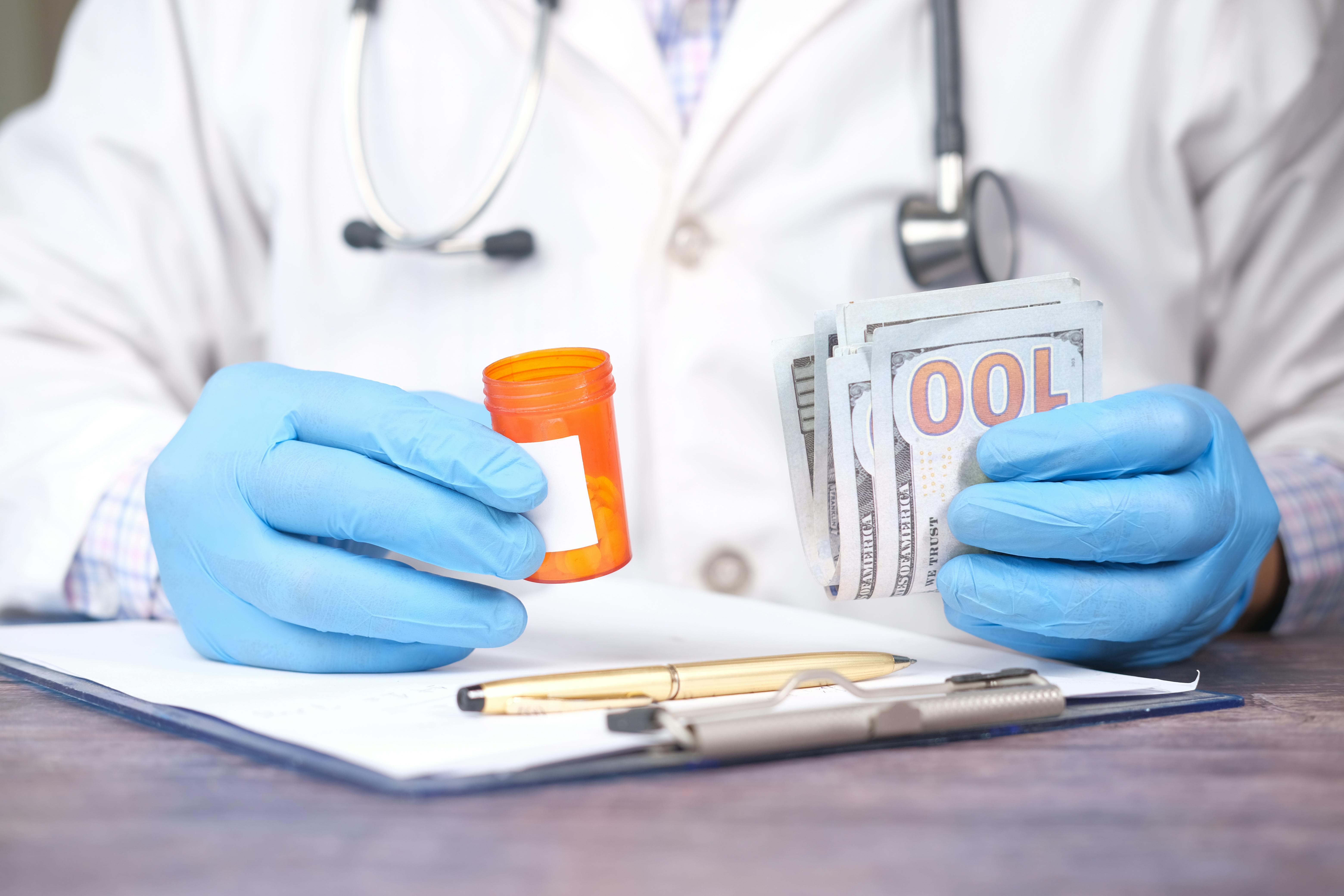 Doctor holding a pill bottle and money | Source: Pexels