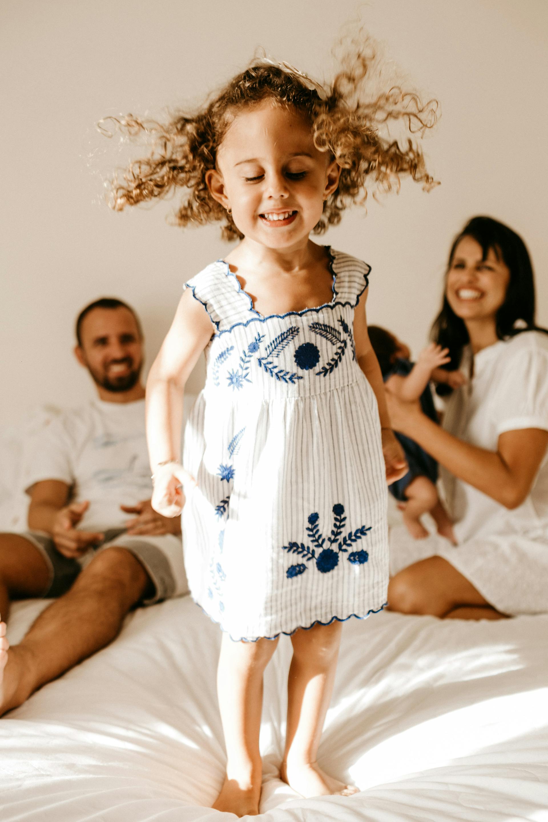 A happy little girl standing on a bed | Source: No source