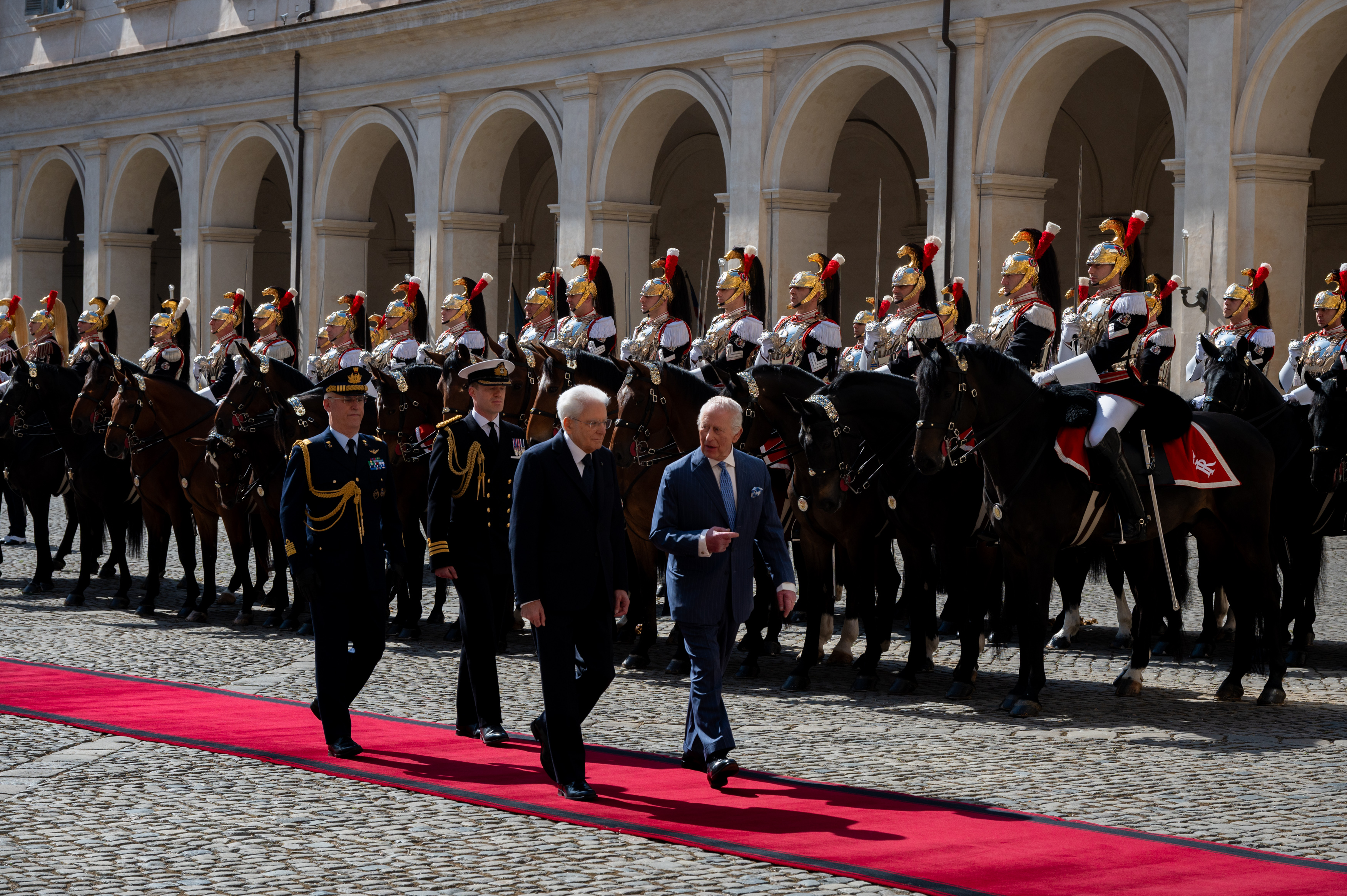 The regal pageantry of Charles' Italian welcome is on full display as the monarch walks beside President Mattarella, backed by a column of mounted guards in traditional dress. The image conveys the symbolic strength of tradition — both British and Italian — in moments of international diplomacy.