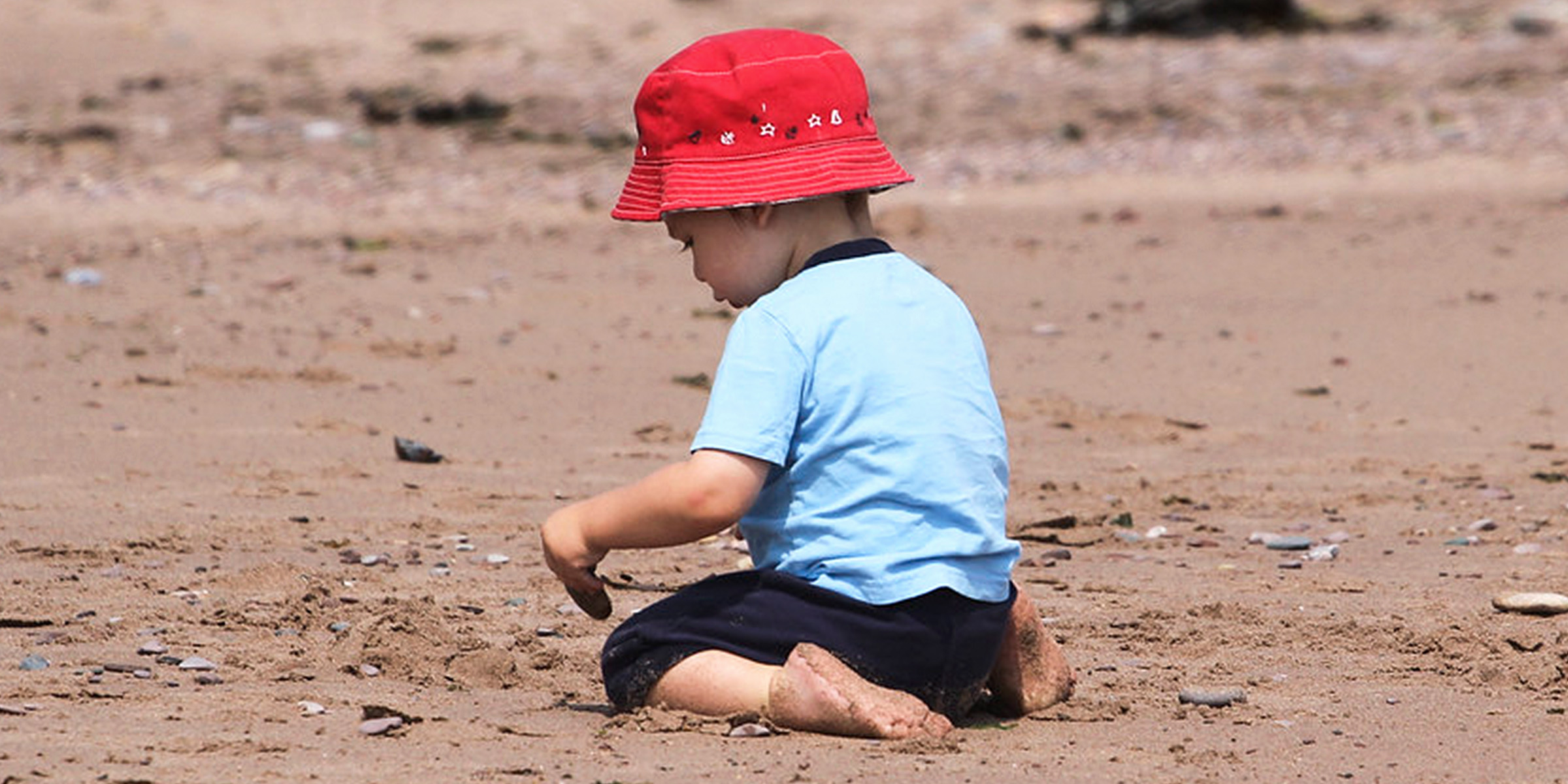 A little boy sitting on the sand | Source: Flickr