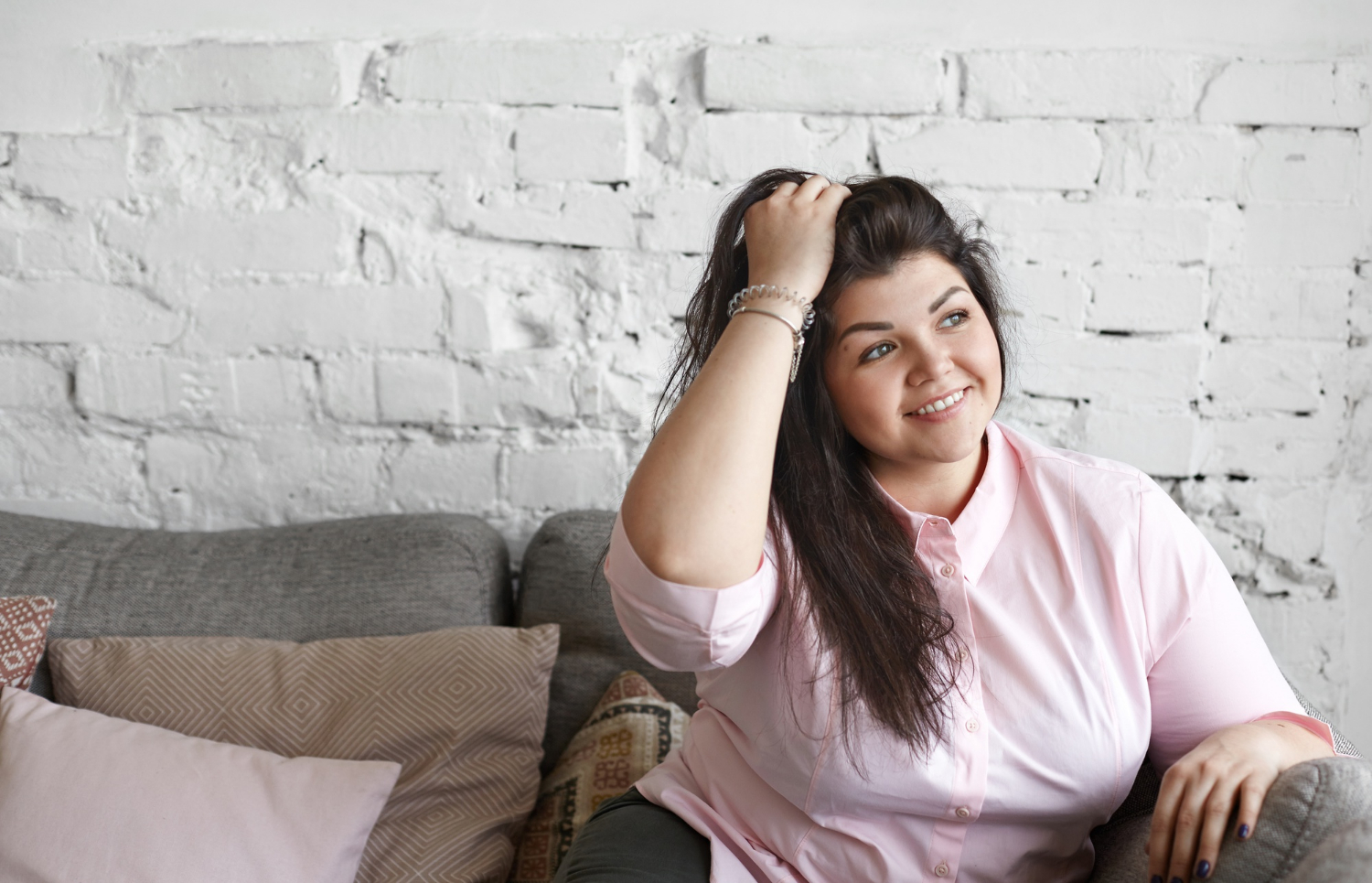 A woman sitting on the couch and posing confidently | Source: Freepik