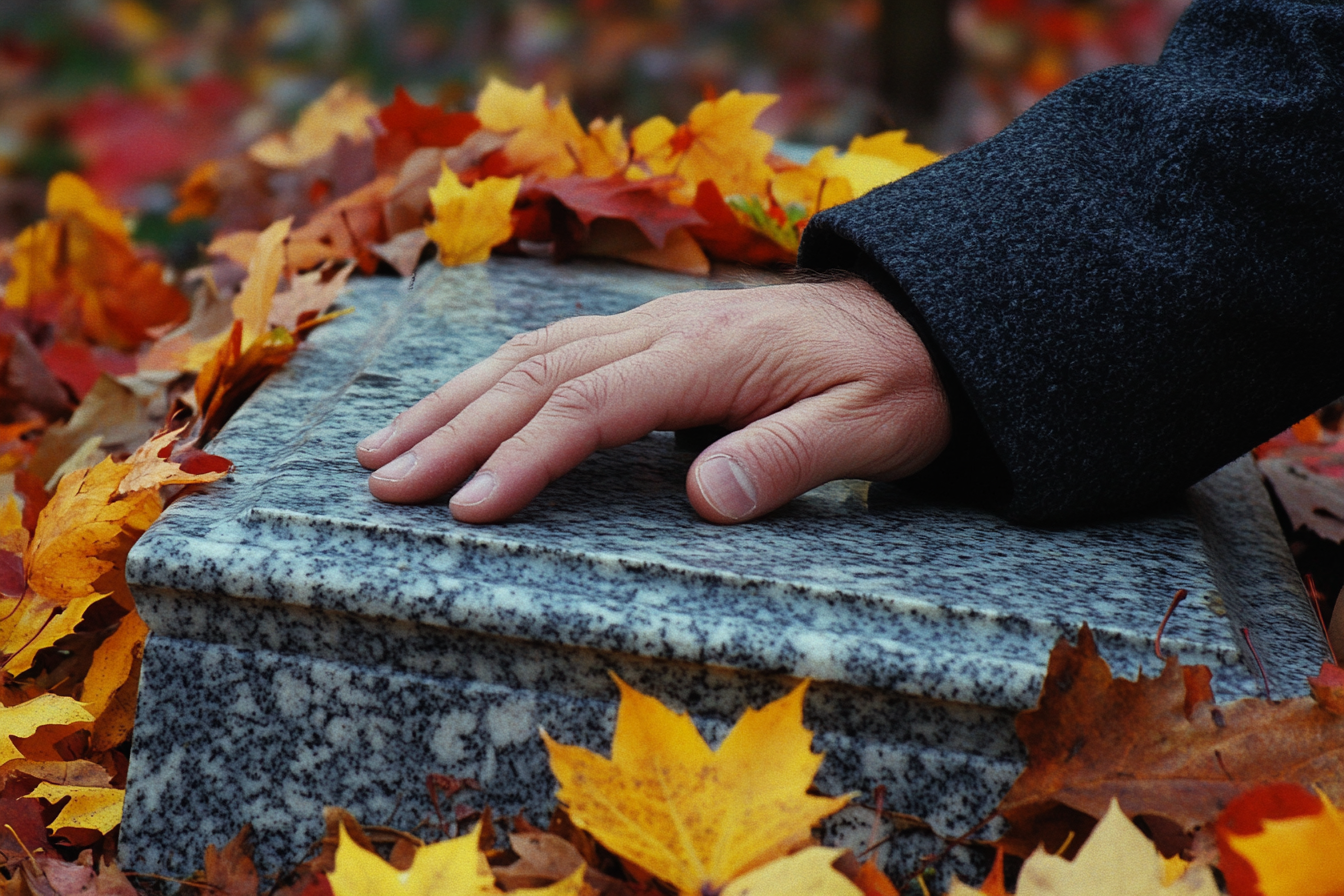 A man's hand resting on a gravestone | Source: no source