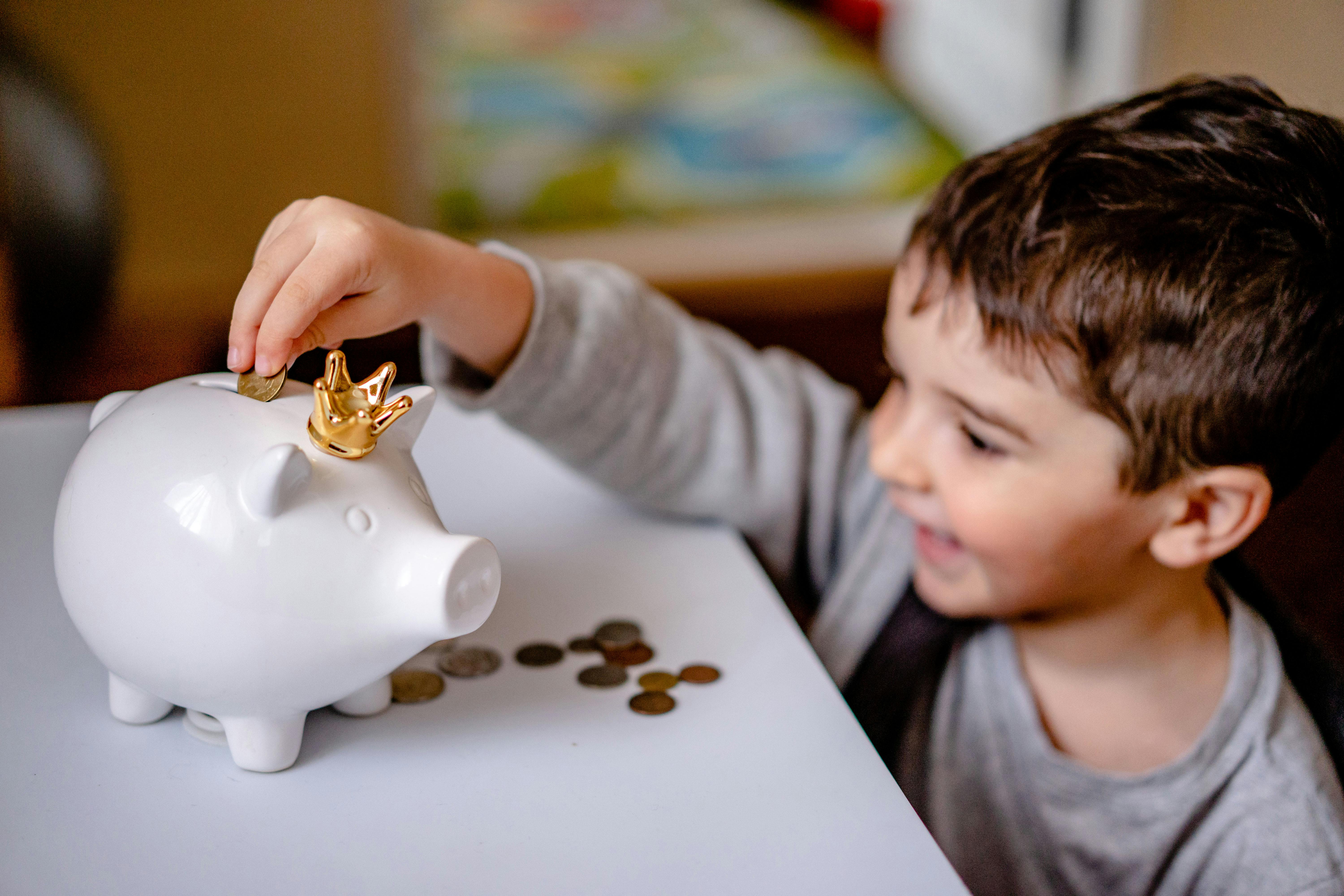 Kid putting money in a piggy bank | Source: Pexels