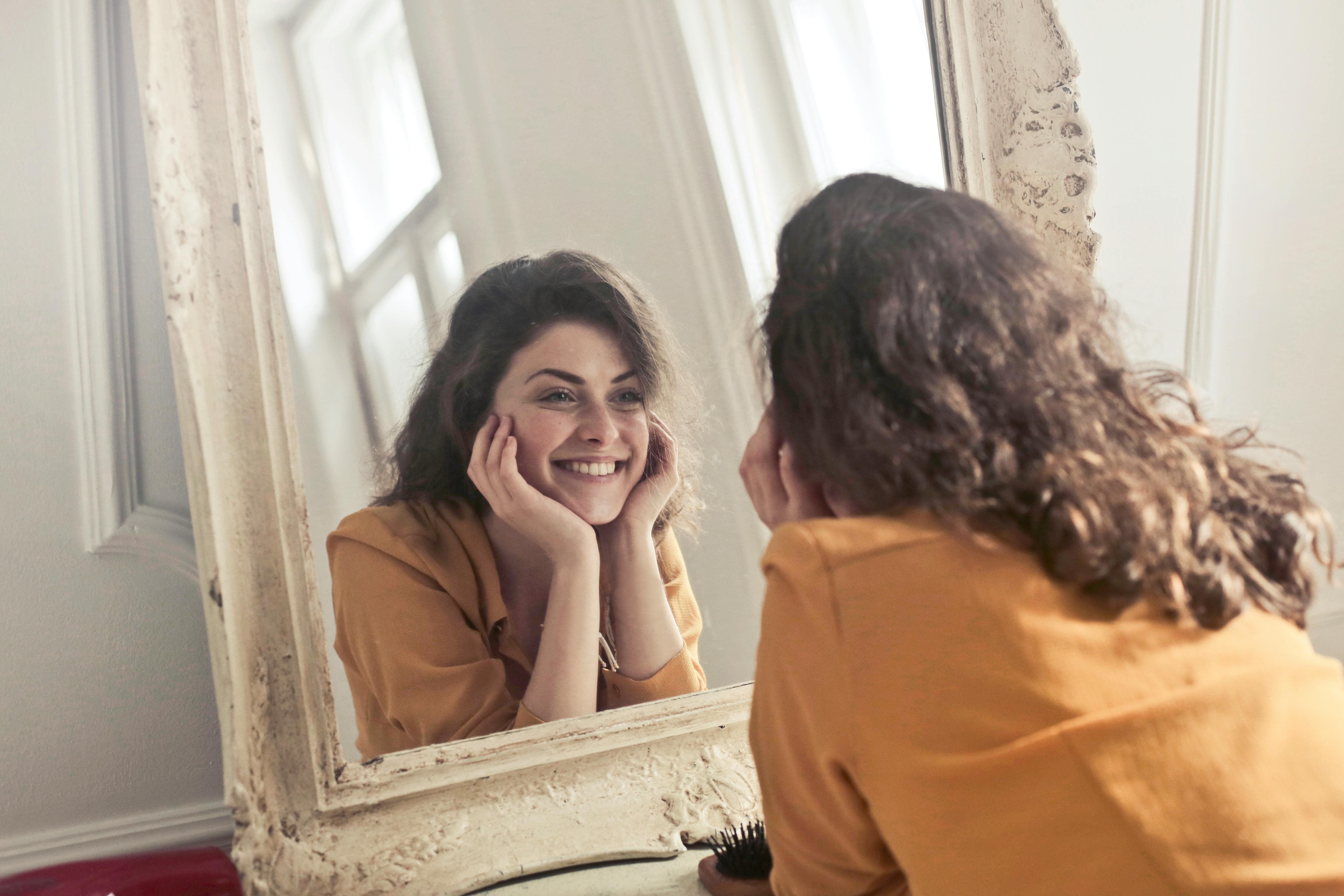 Woman smiling in front of a mirror | Source: Pexels