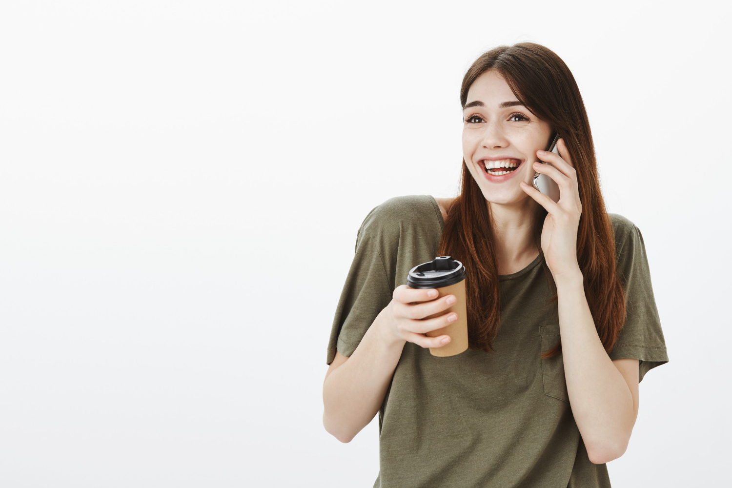 A woman holding a coffee cup and laughing while talking on the phone | Source: Freepik