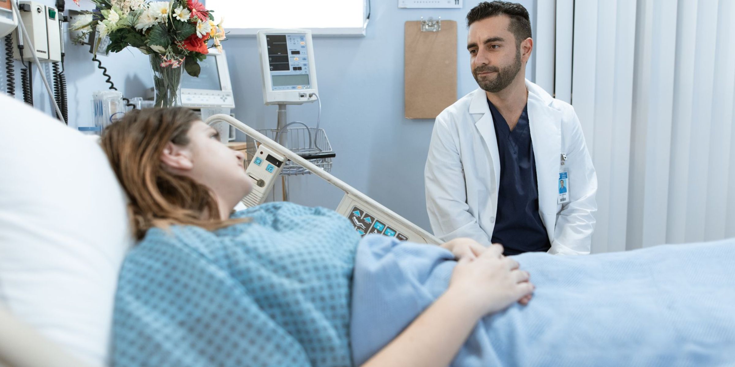 A doctor sitting beside a hospital bed and speaking with a patient | Source: Pexels