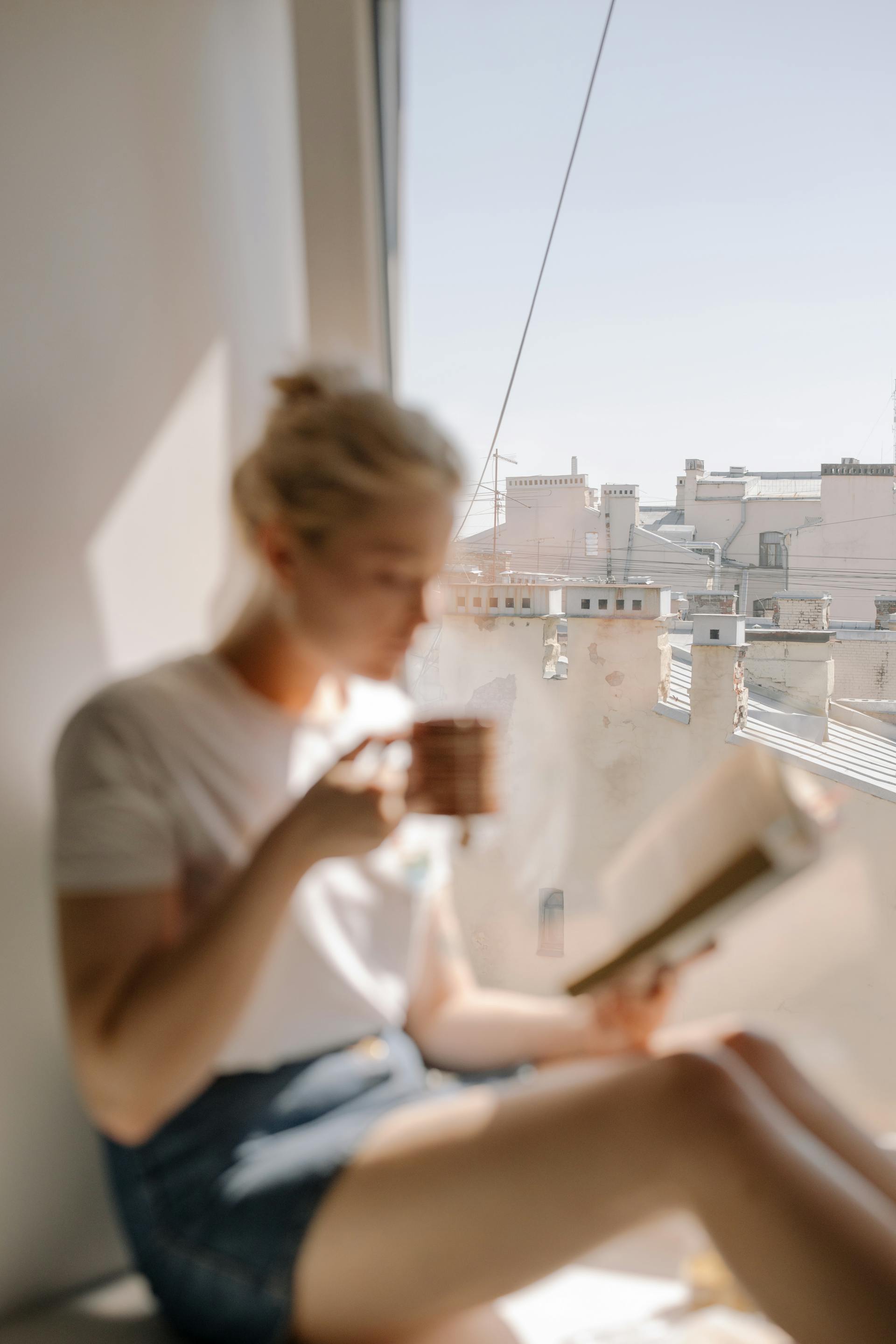 A woman drinking coffee near and apartment window | Source: Pexels