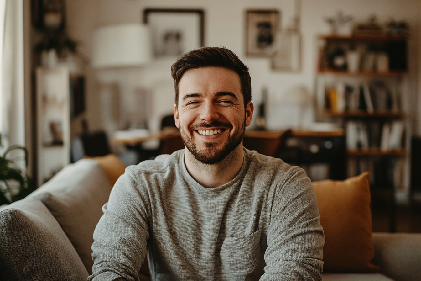 A smiling man on a sofa | Source: no source