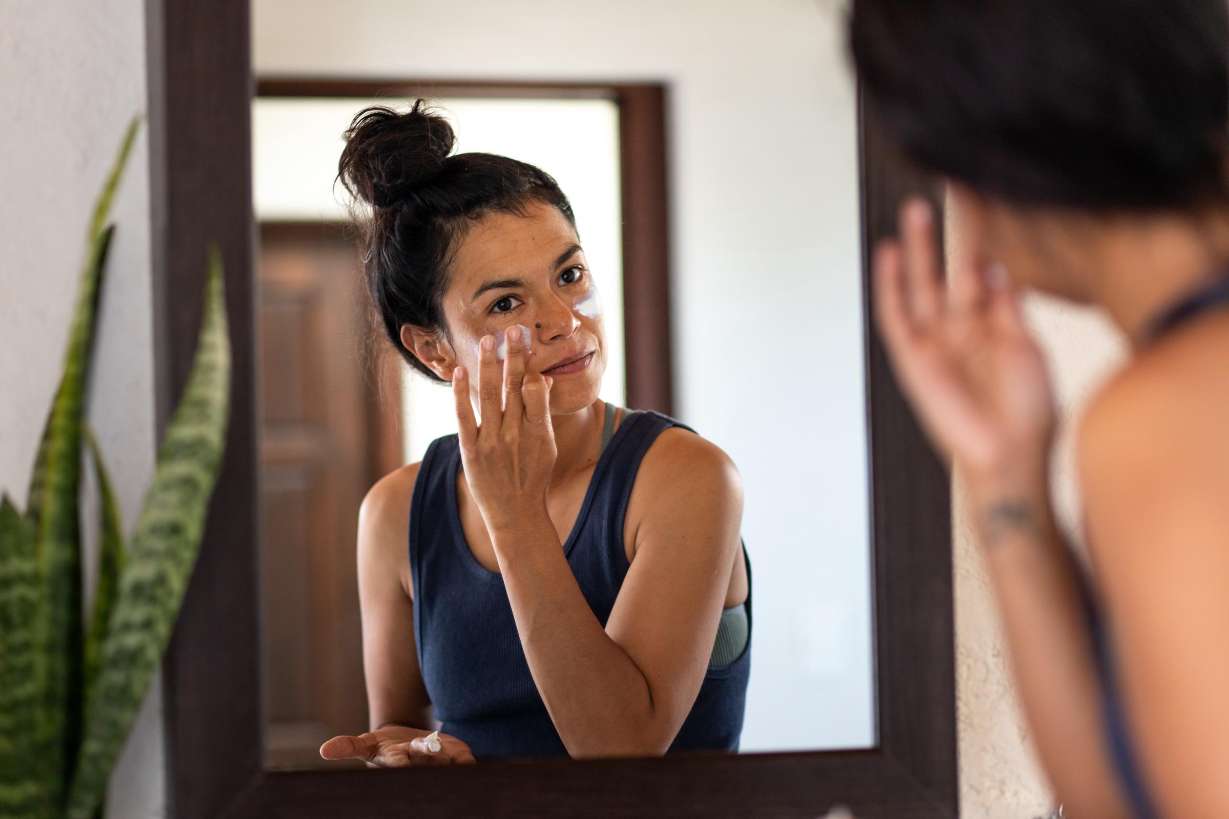 A woman applying sunblock to her face | Source: Getty Images