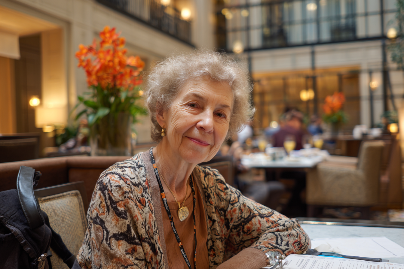 A woman seated at a table in a hotel restaurant smiling at someone | Source: No source