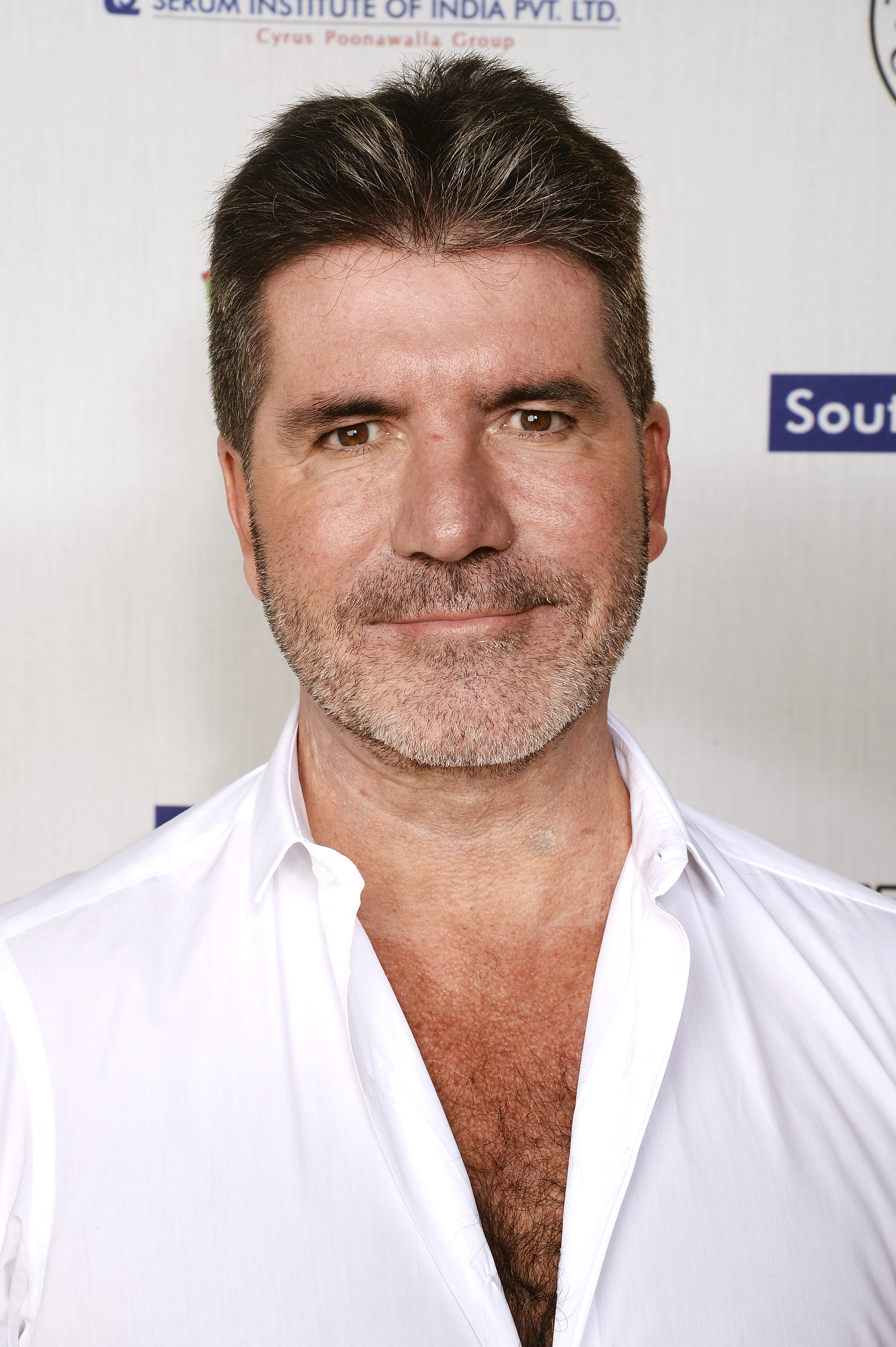 Effortlessly blending elegance and ease, Cowell dons an open-collared white shirt at the British Asian Trust event in 2016. Inside London's Natural History Museum, he balances informal charm with old-world grandeur.