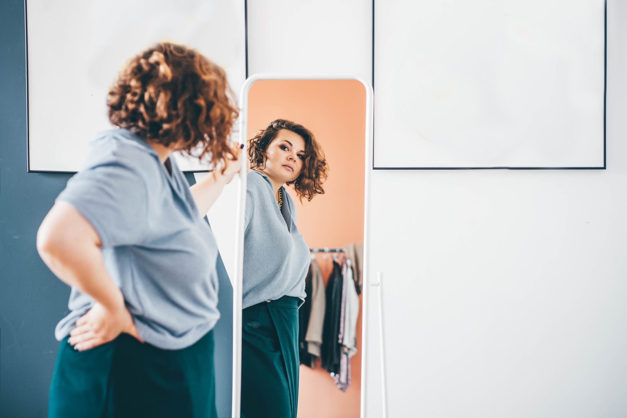 A woman admires choice of clothes standing in front of large mirror I Source : Getty Images