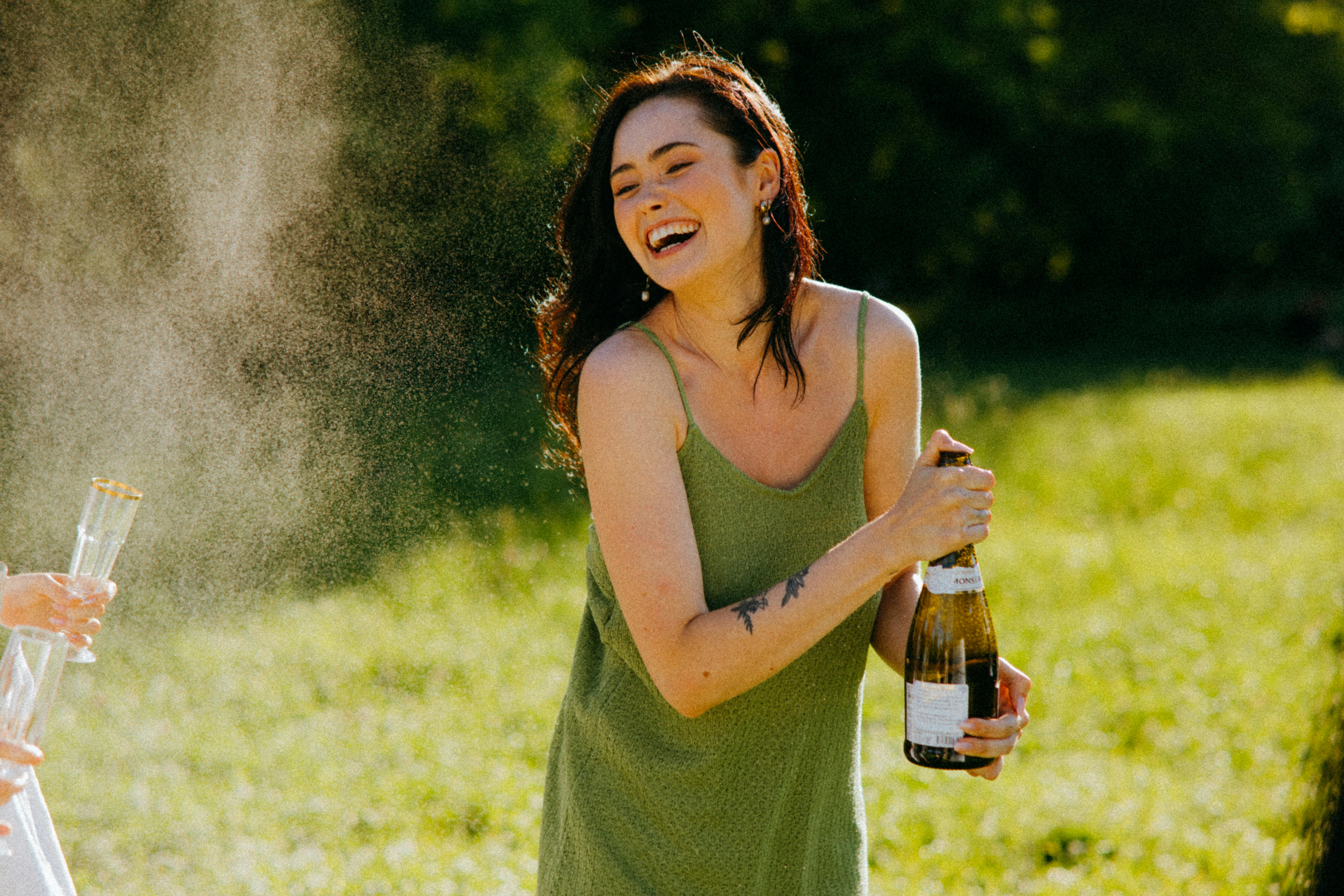 A woman laughing while holding a bottle | Source: Pexels