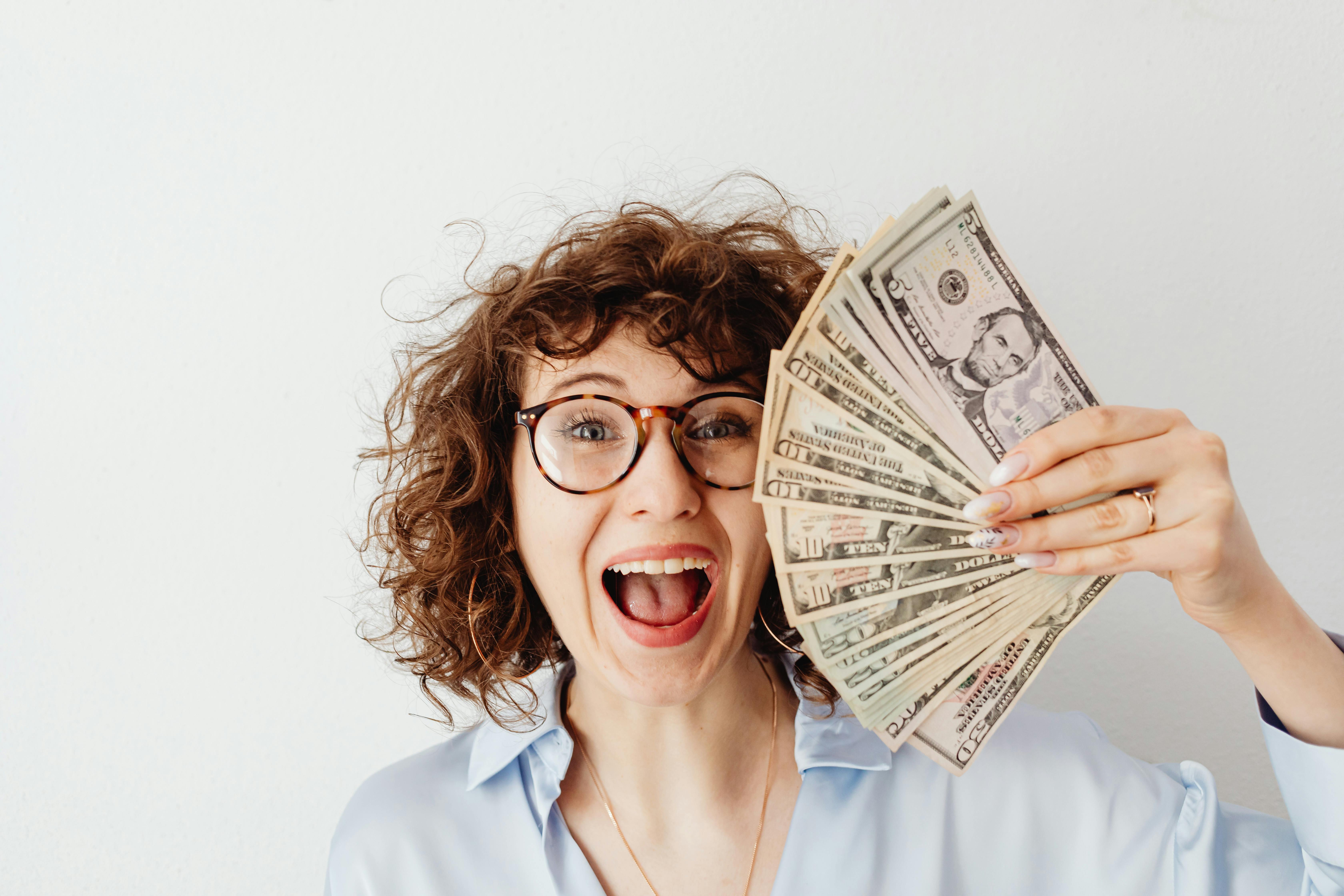 A happy woman holding money | Source: Pexels
