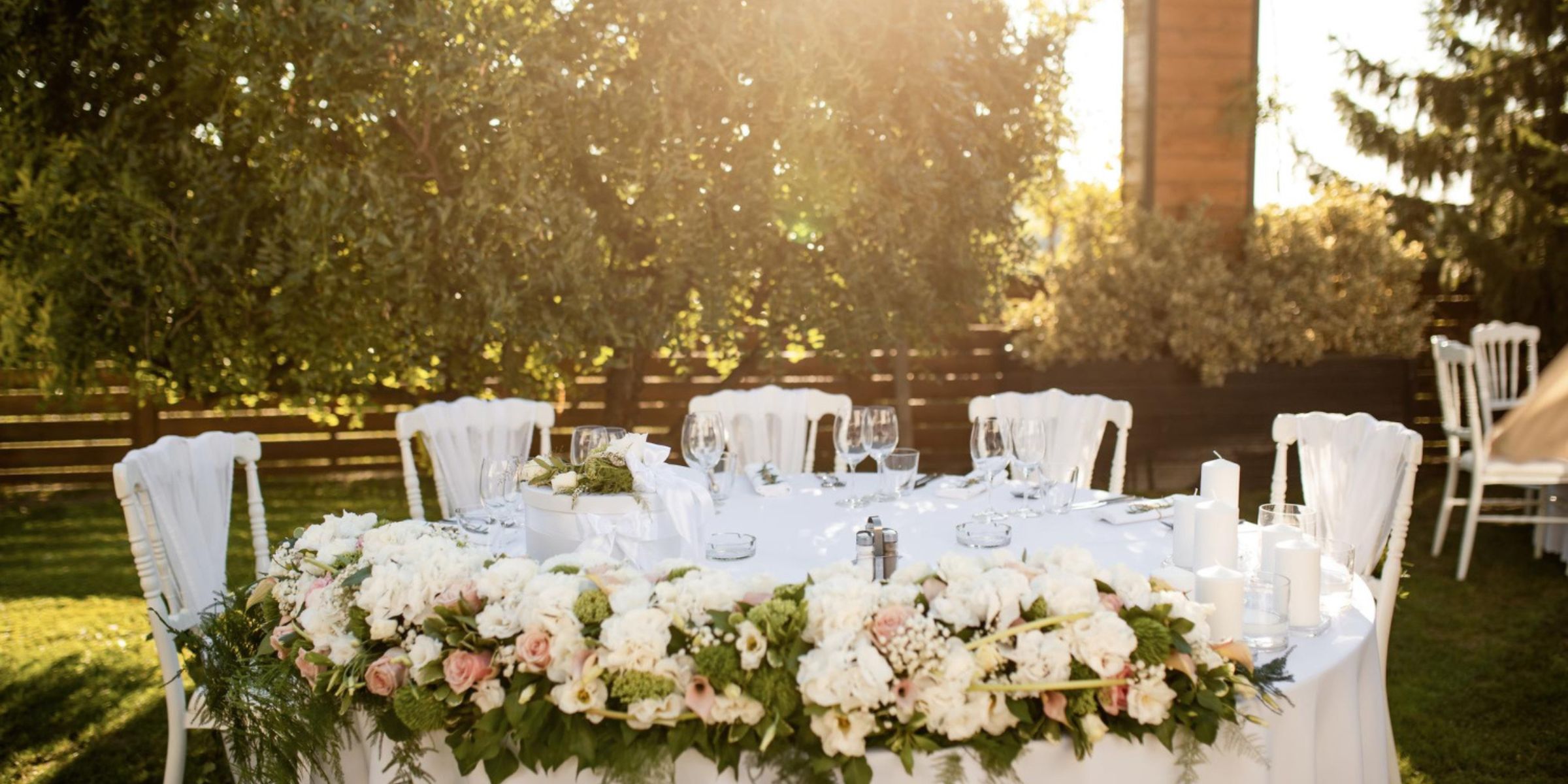 Wedding reception table decorated with white floral centerpieces outdoors | Source: No source