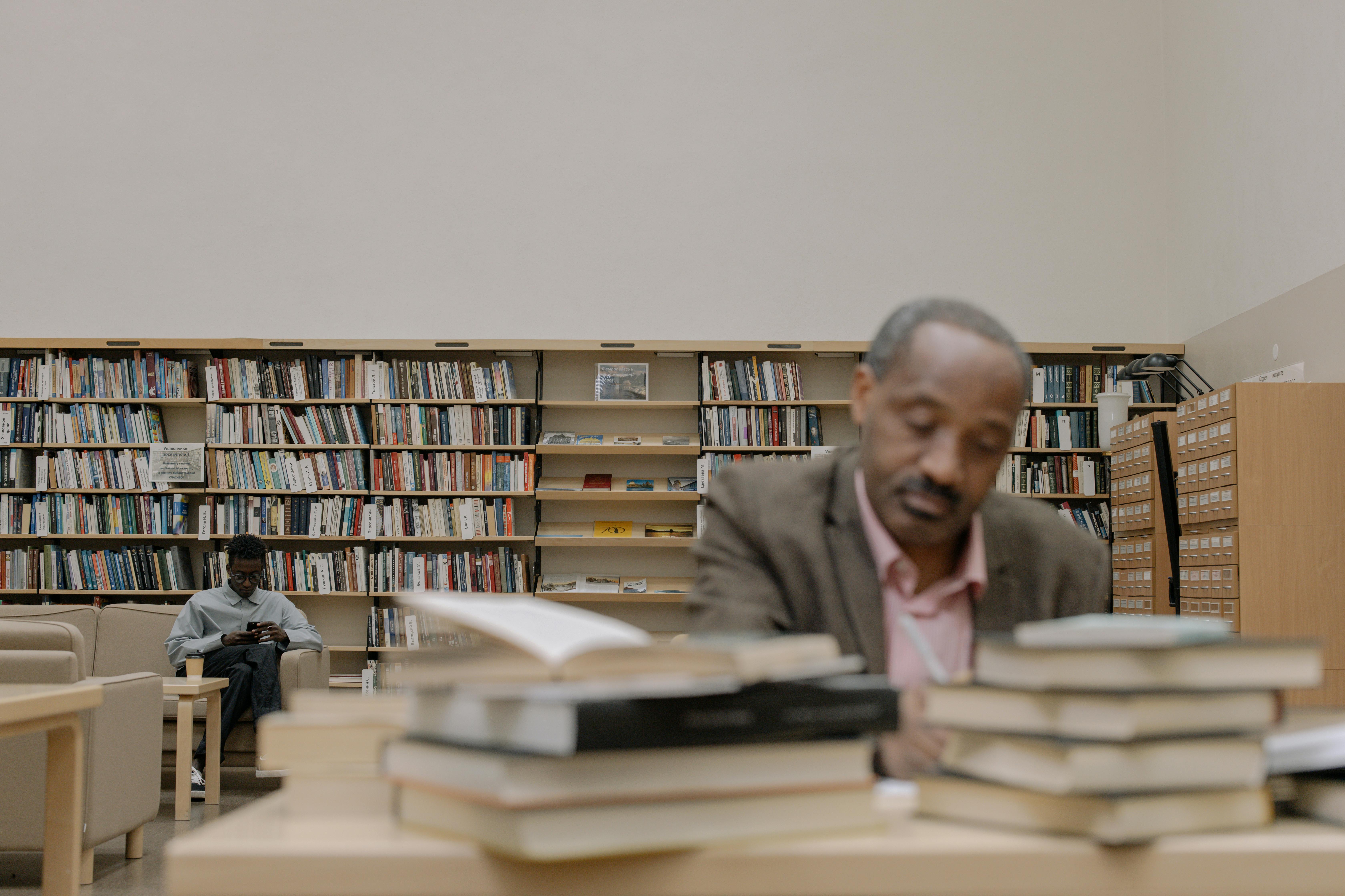 A man in a gray shirt sits near a wooden table | Source: Pexels