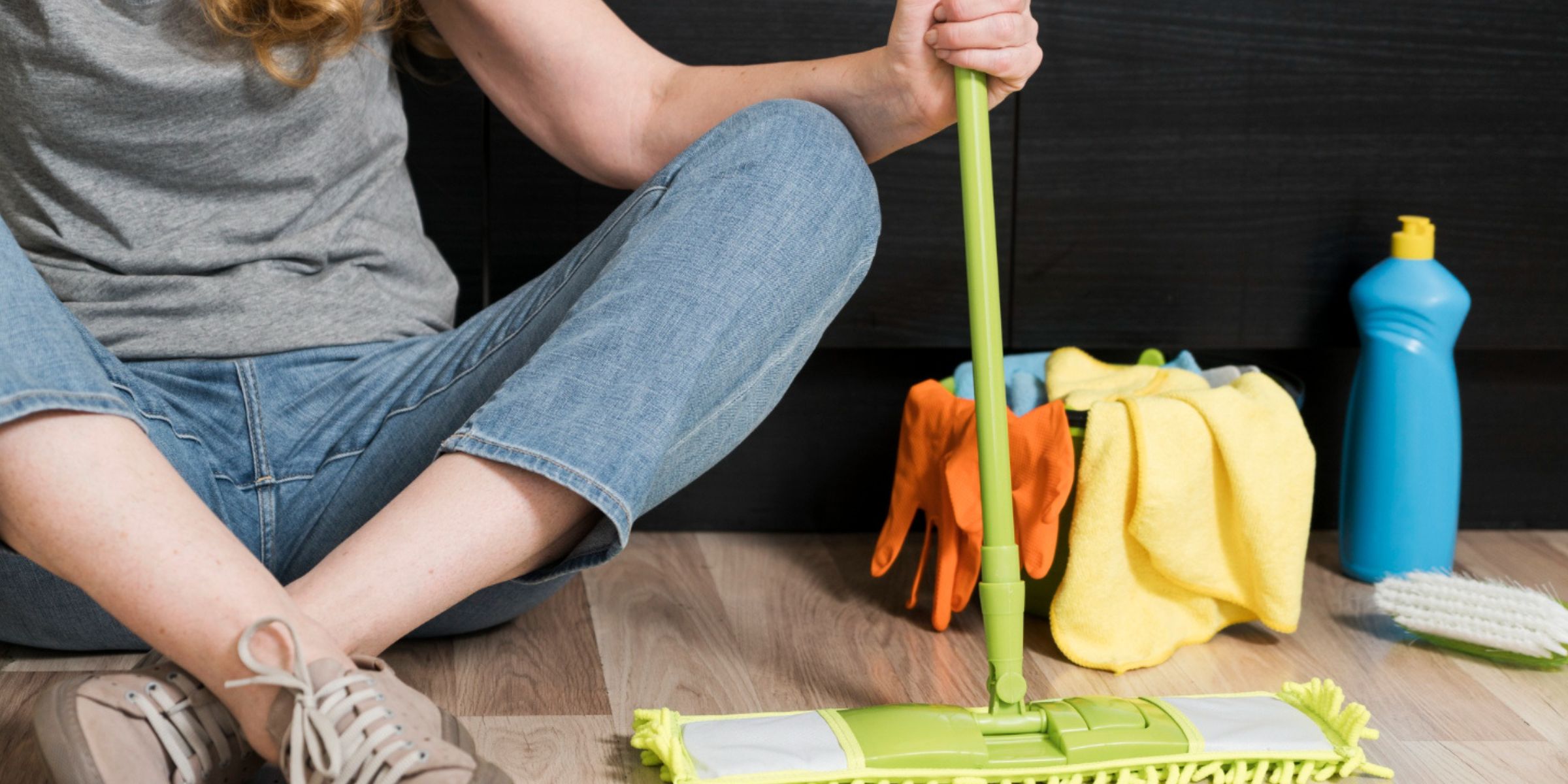 A woman sitting on the floor with cleaning supplies and a mop nearby | Source: No source