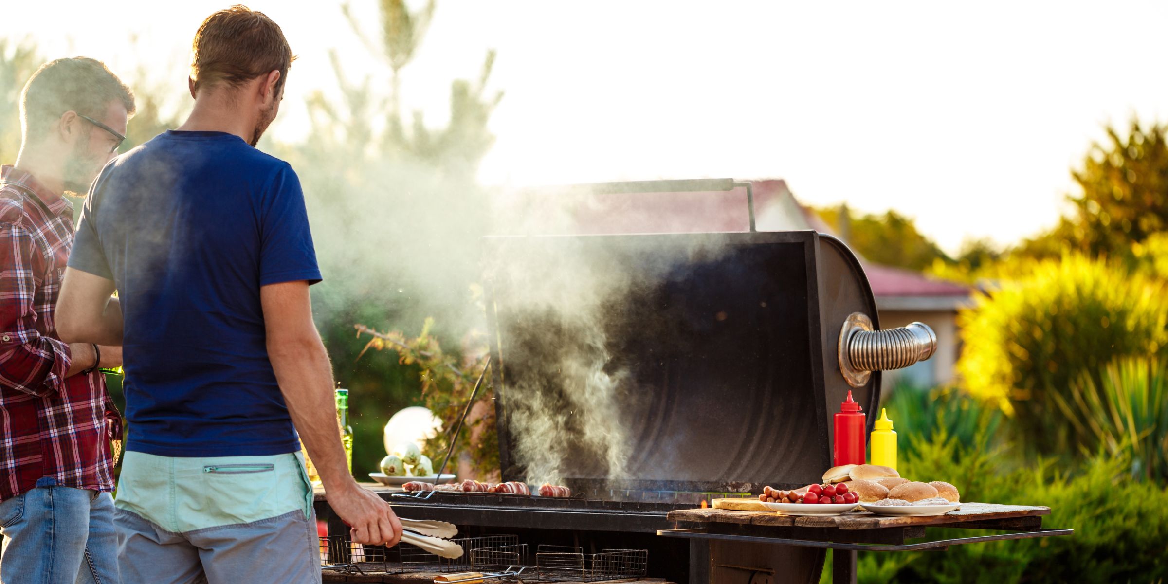 Two young men standing at a barbecue grill | Source: No source