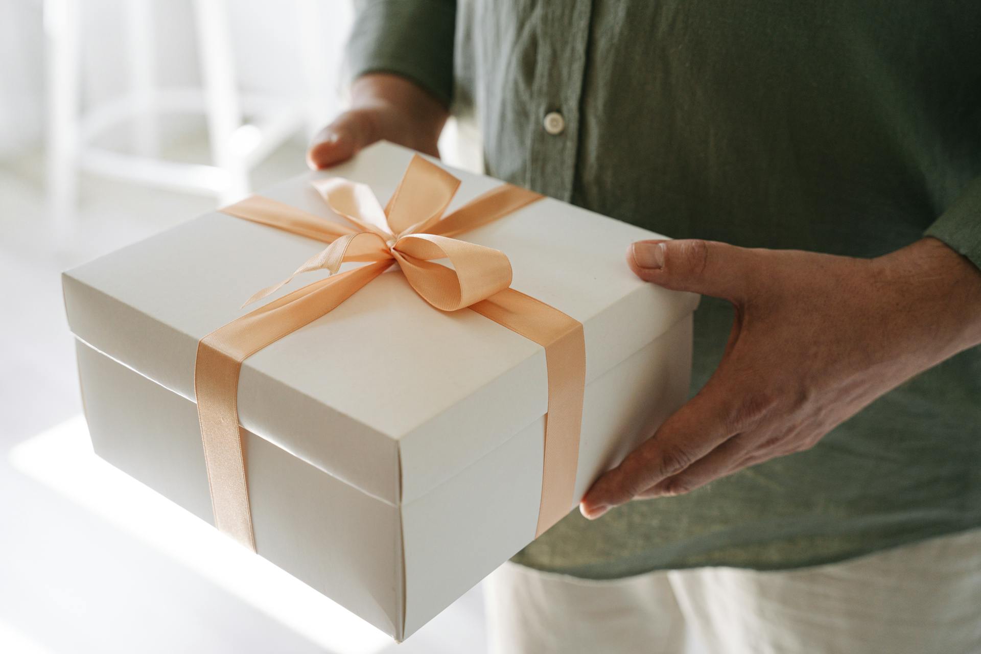 A man holding a box wrapped in orange satin ribbon | Source: Pexels