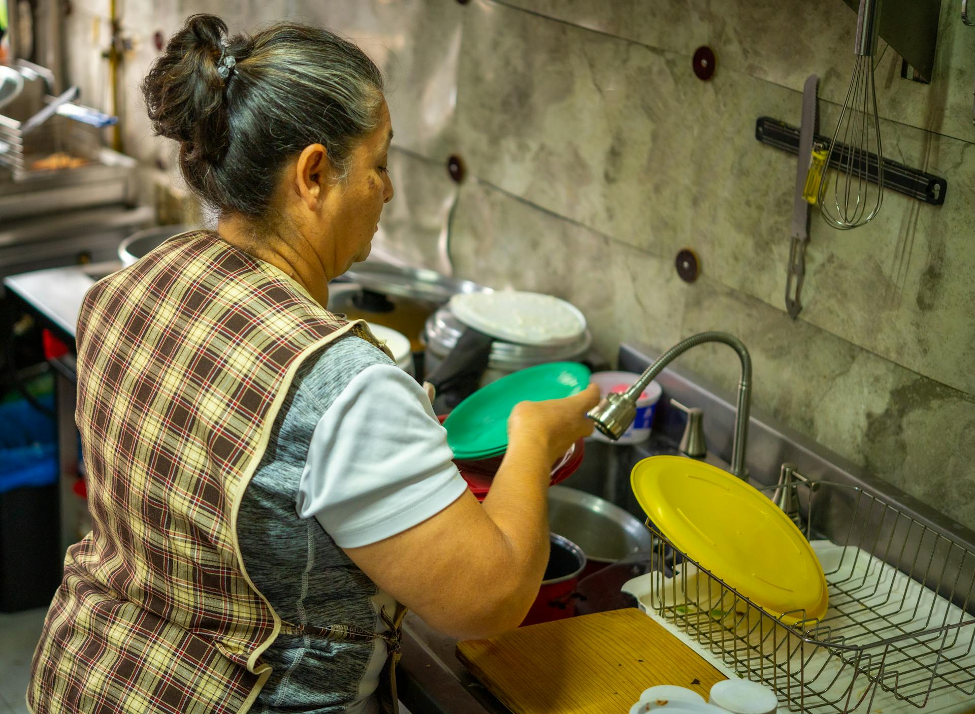 An older lady washing dishes | Source: Pexels