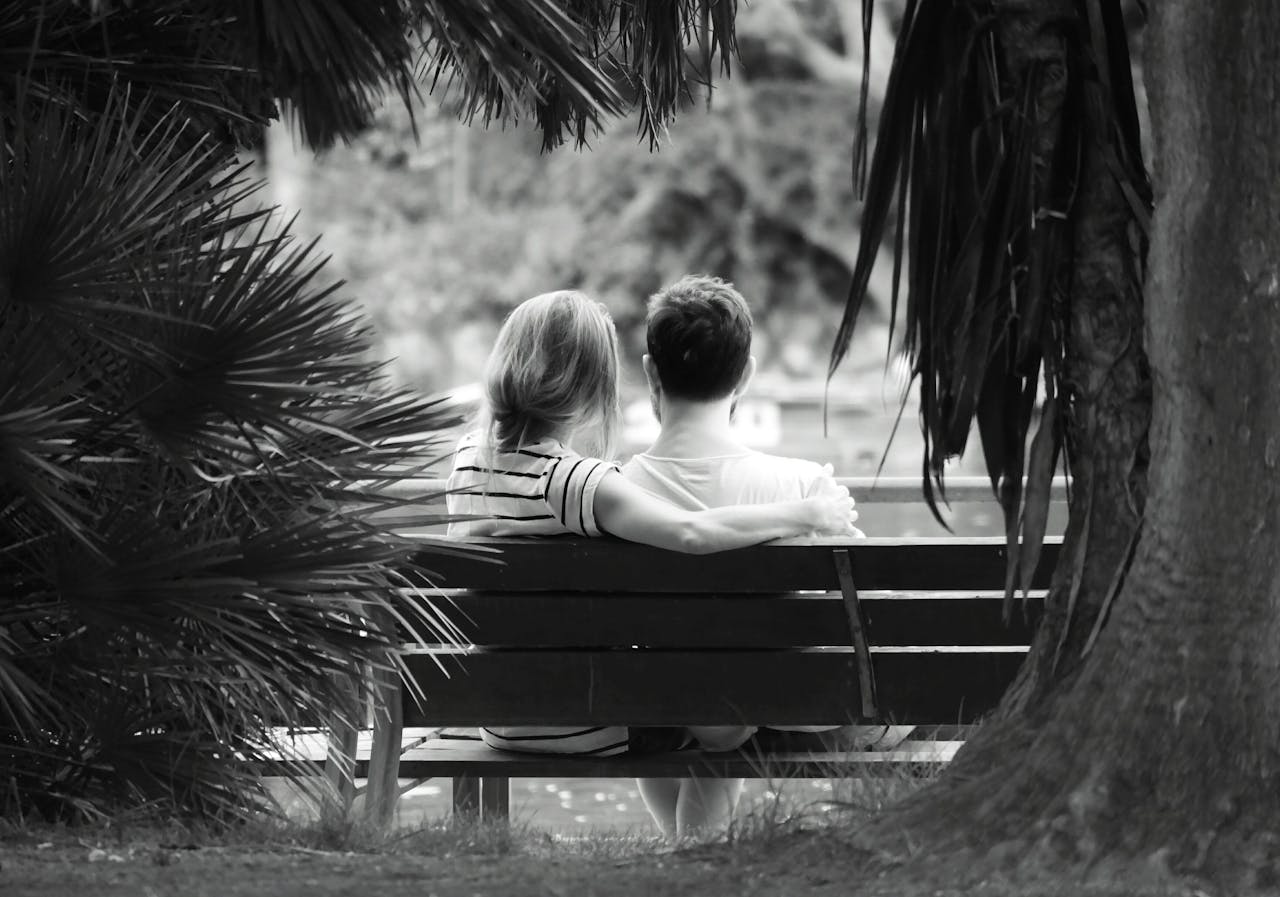 A couple sitting on a wooden bench | Source: Pexels