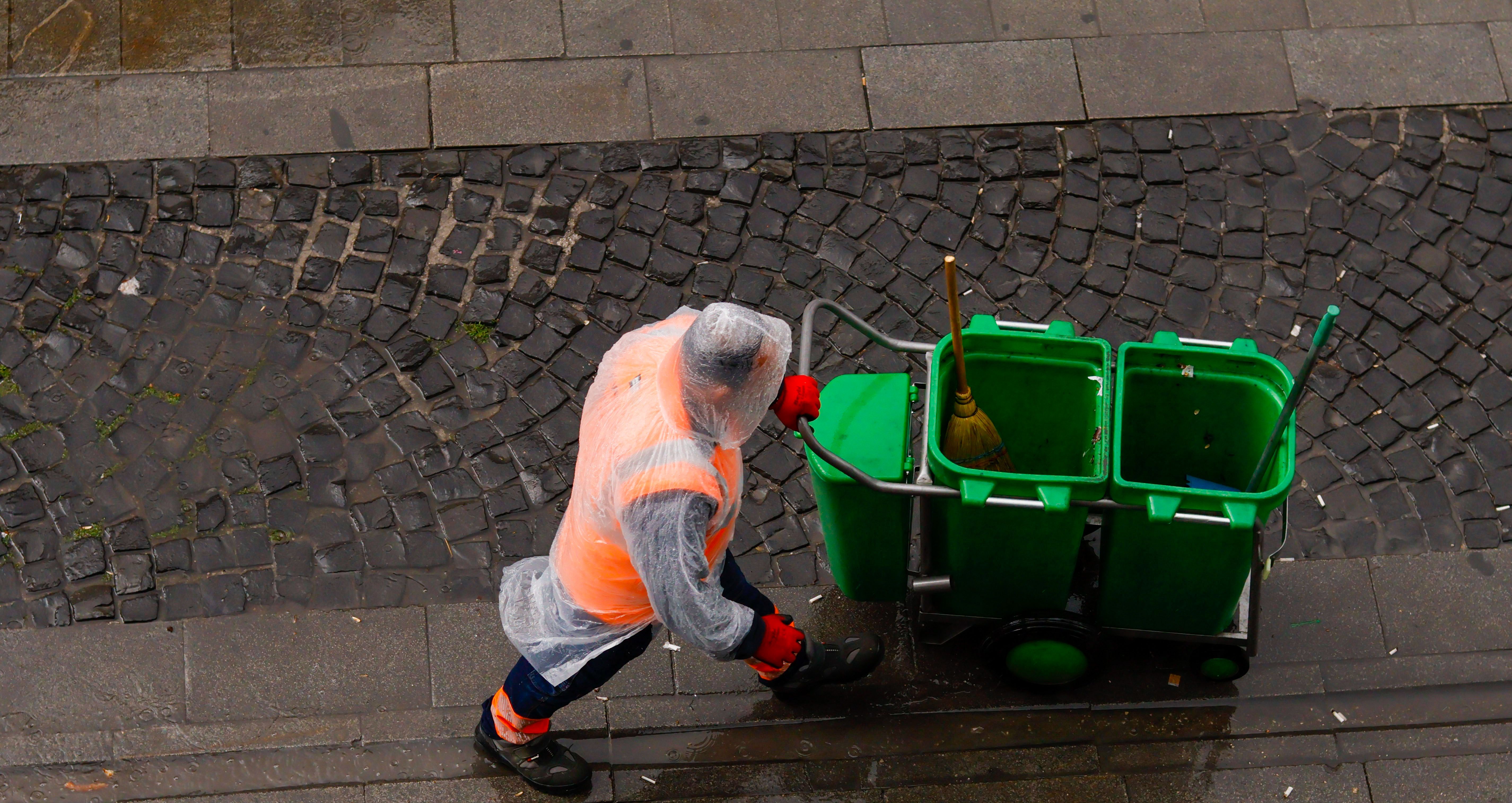 A janitor walking with trashcans | Source: Pexels
