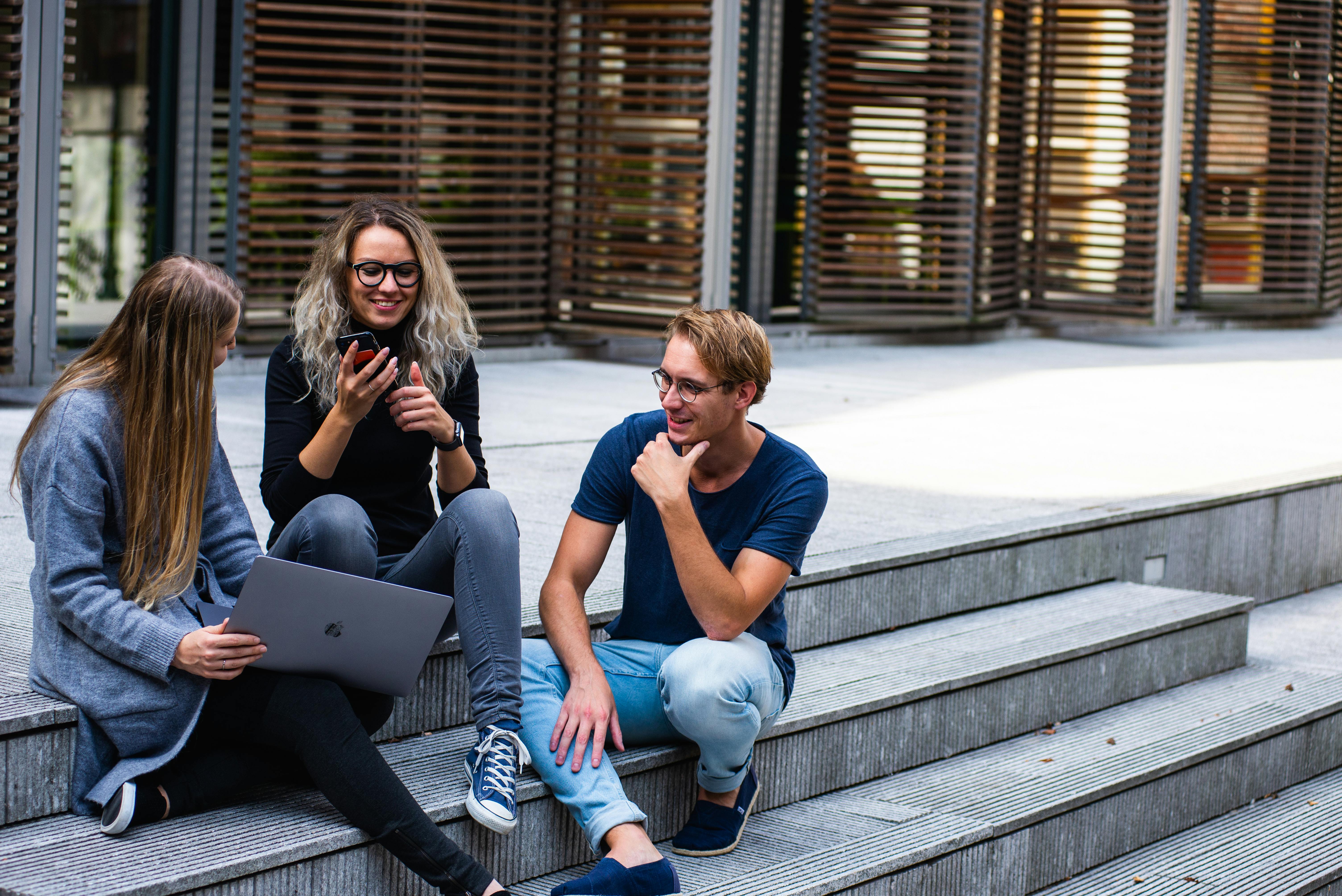 Three people sitting on stairs talking to each other | Source: Pexels