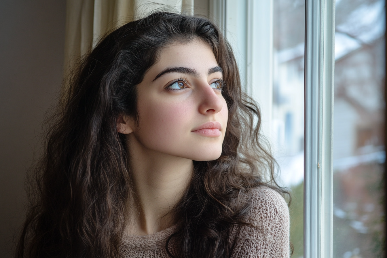 A woman staring dreamily out a window | Source: No source