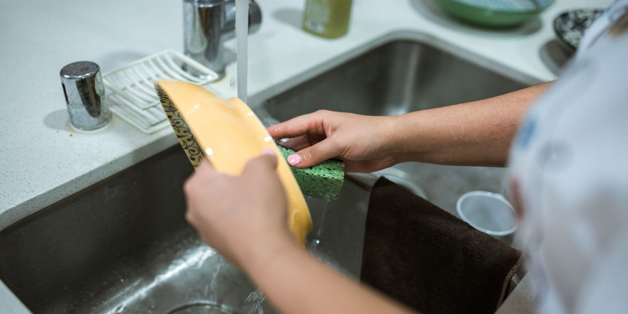 A person washing a dish at the kitchen sink while rinsing it under running water | Source: Pexels
