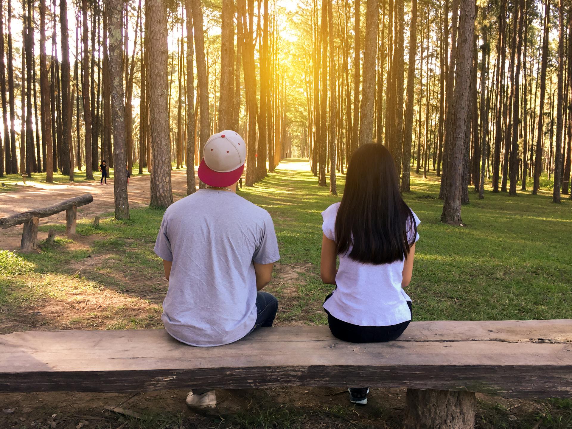 Man and woman sitting on a bench in the woods | Source: Pexels