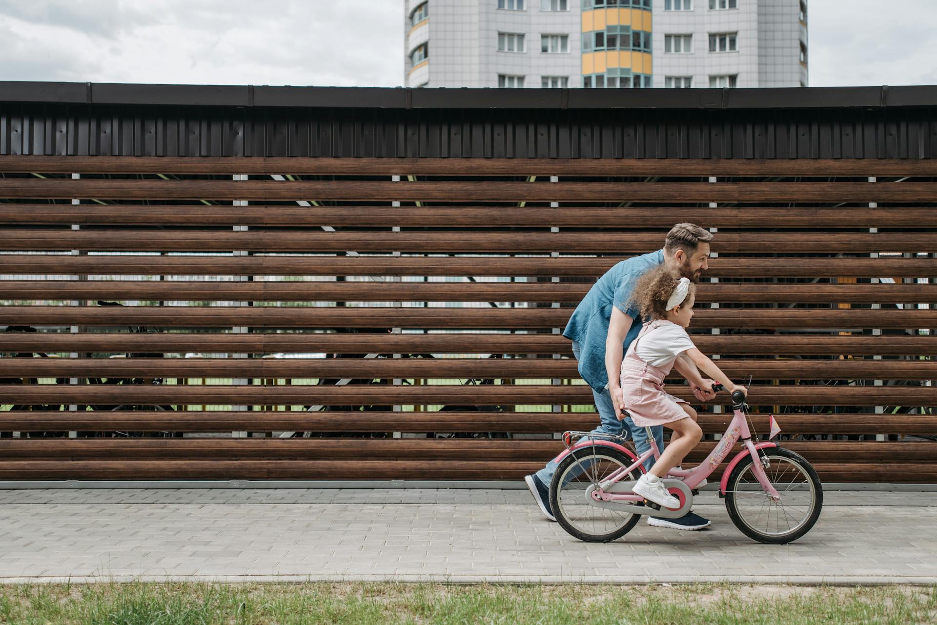 A man teaching his little daughter to ride a bike | Source: Pexels