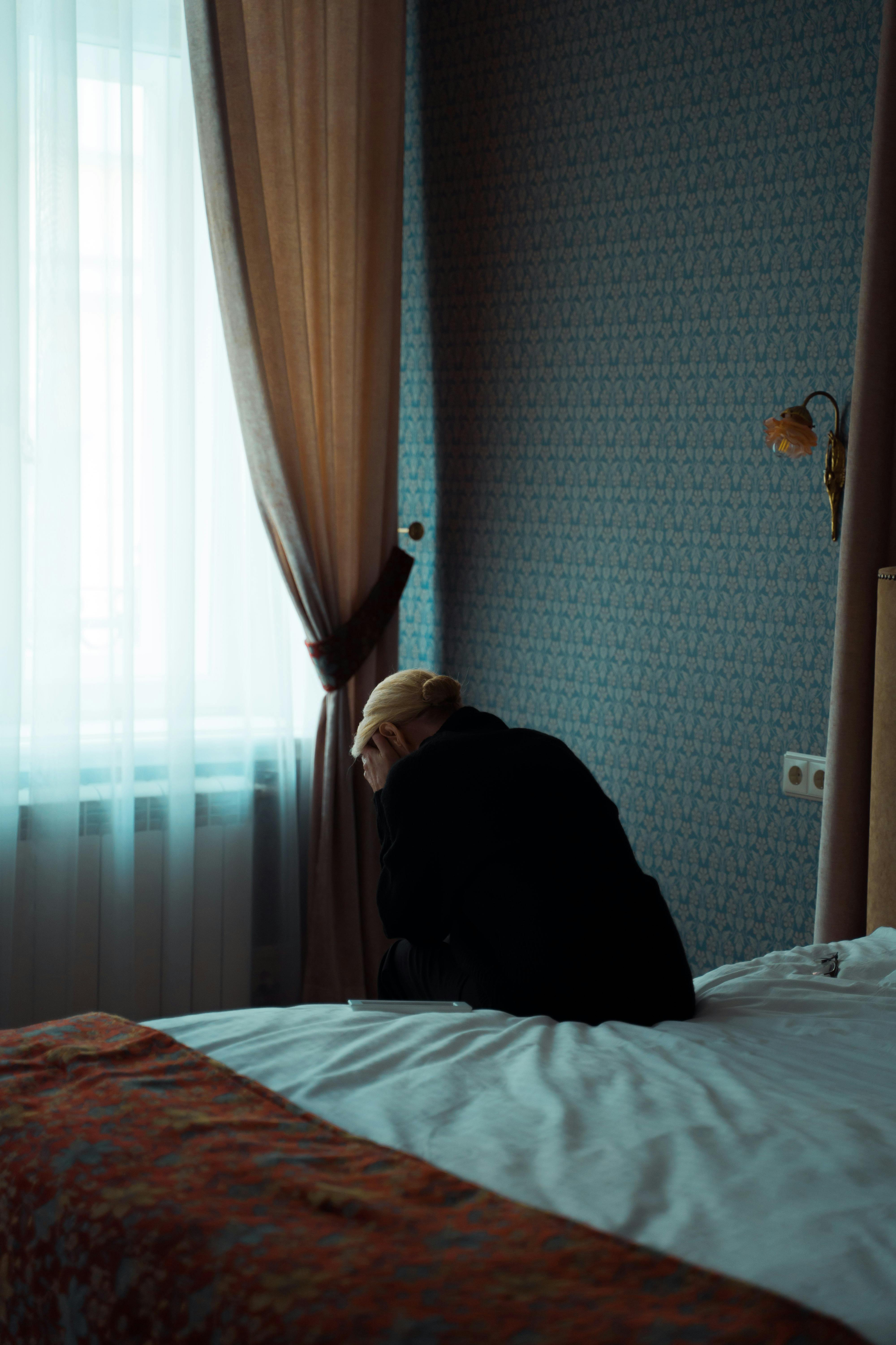 An unhappy woman sitting on a bed | Source: Pexels