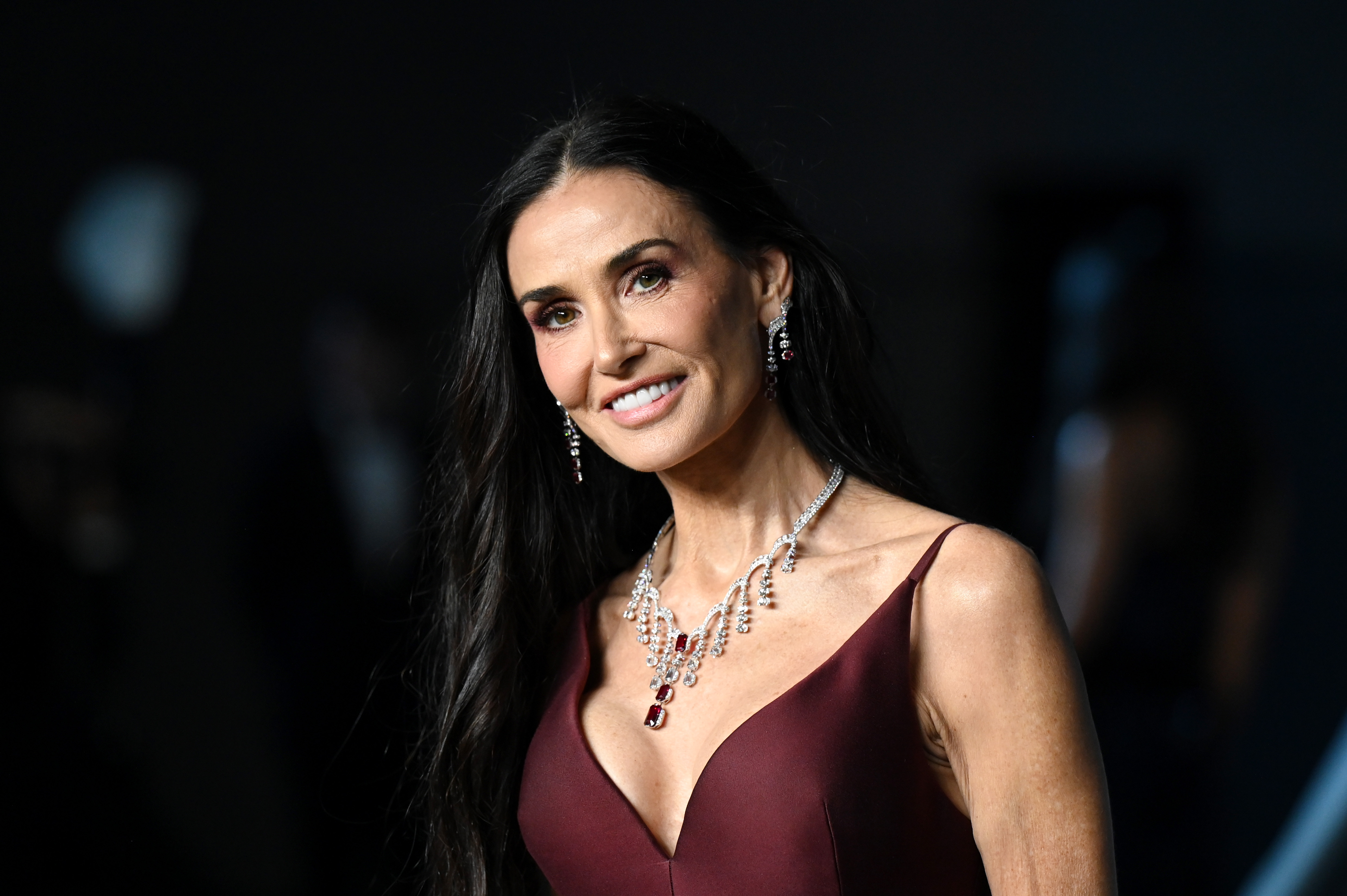 Up close and radiant — Demi Moore shows off a flawless glow and a confident smile, her sparkling ruby necklace perfectly accenting the plunging neckline of her sleek maroon gown.