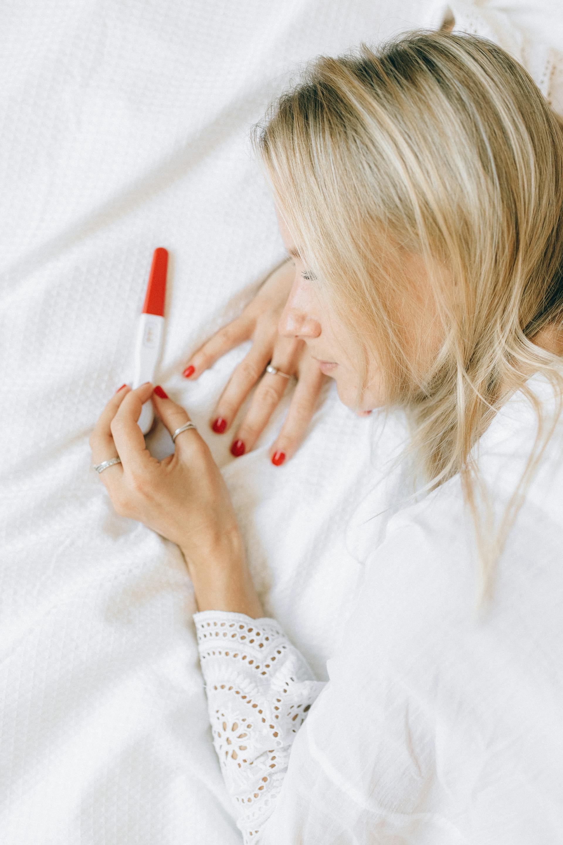A woman staring sadly at a pregnancy test | Source: Pexels