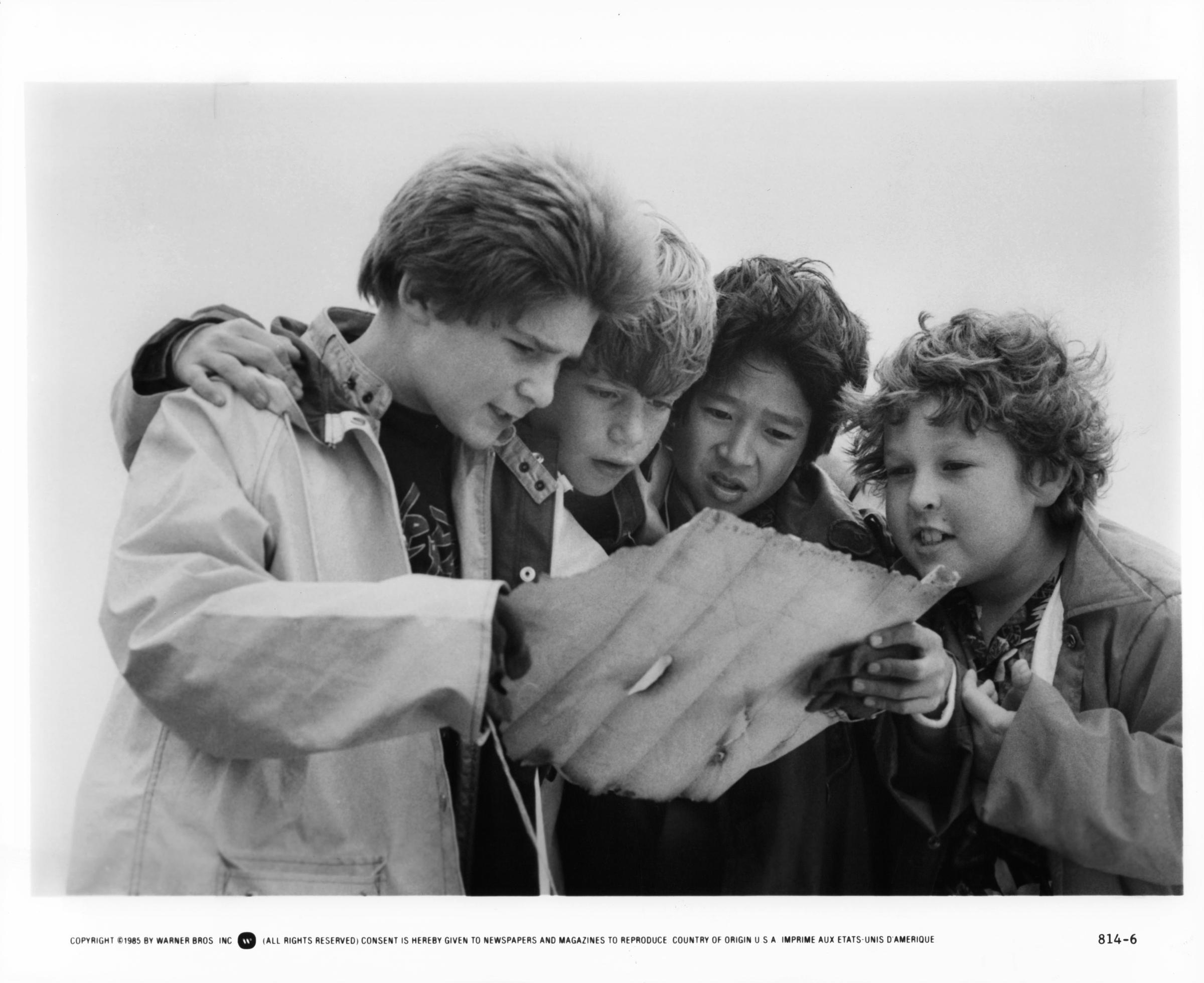 Corey Feldman, Sean Astin, Ke Huy Quan, and Jeff Cohen reading a treasure map in a scene from the film "Goonies," in 1985 | Source: Getty Images