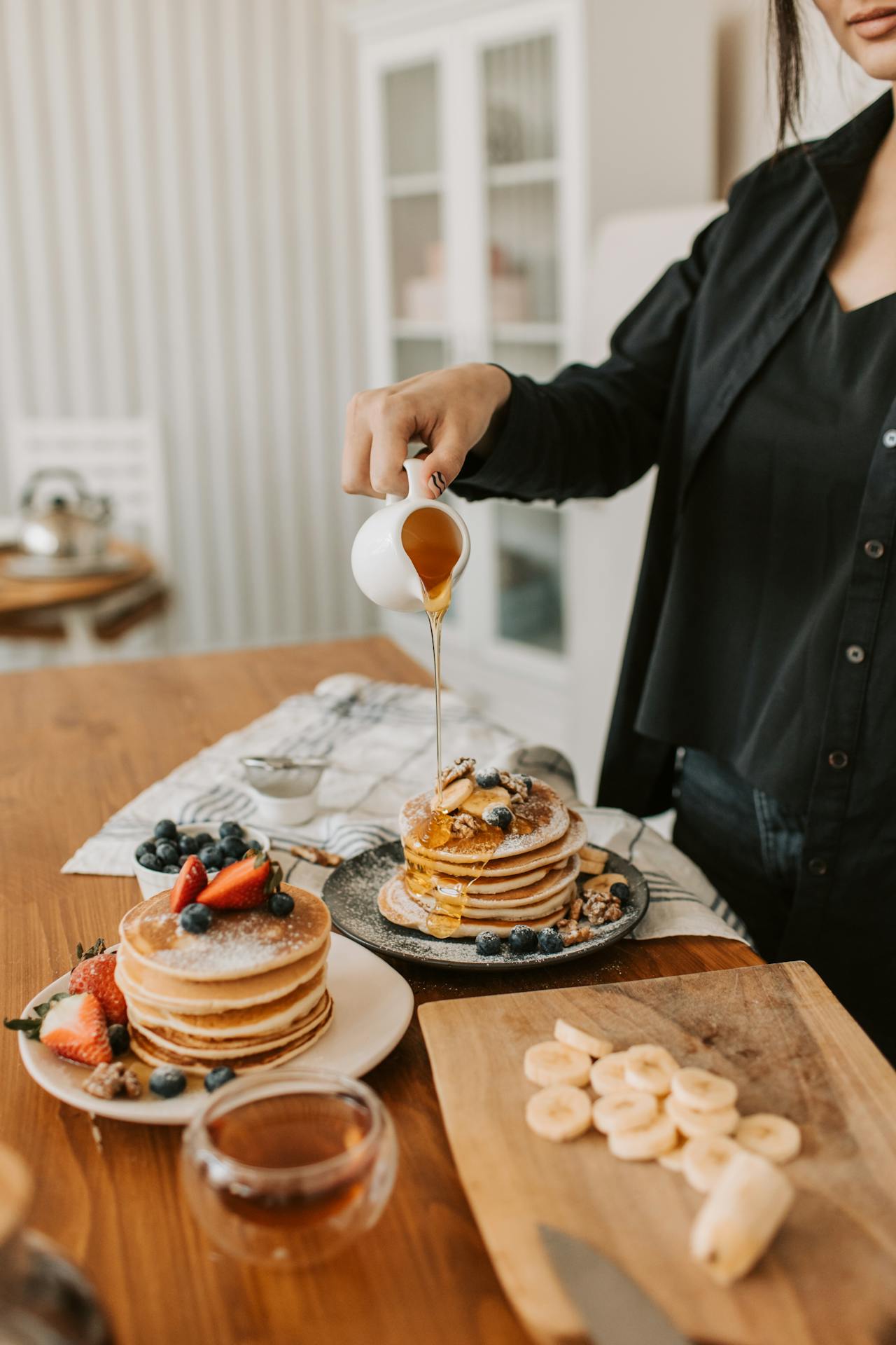 A woman pouring syrup on pancakes | Source: Pexels
