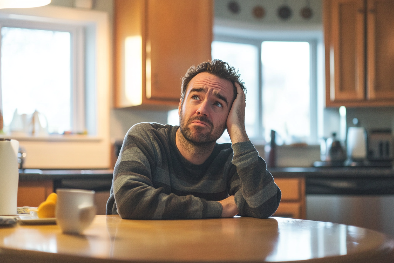 A man sitting in a kitchen looking confused | Source: No source