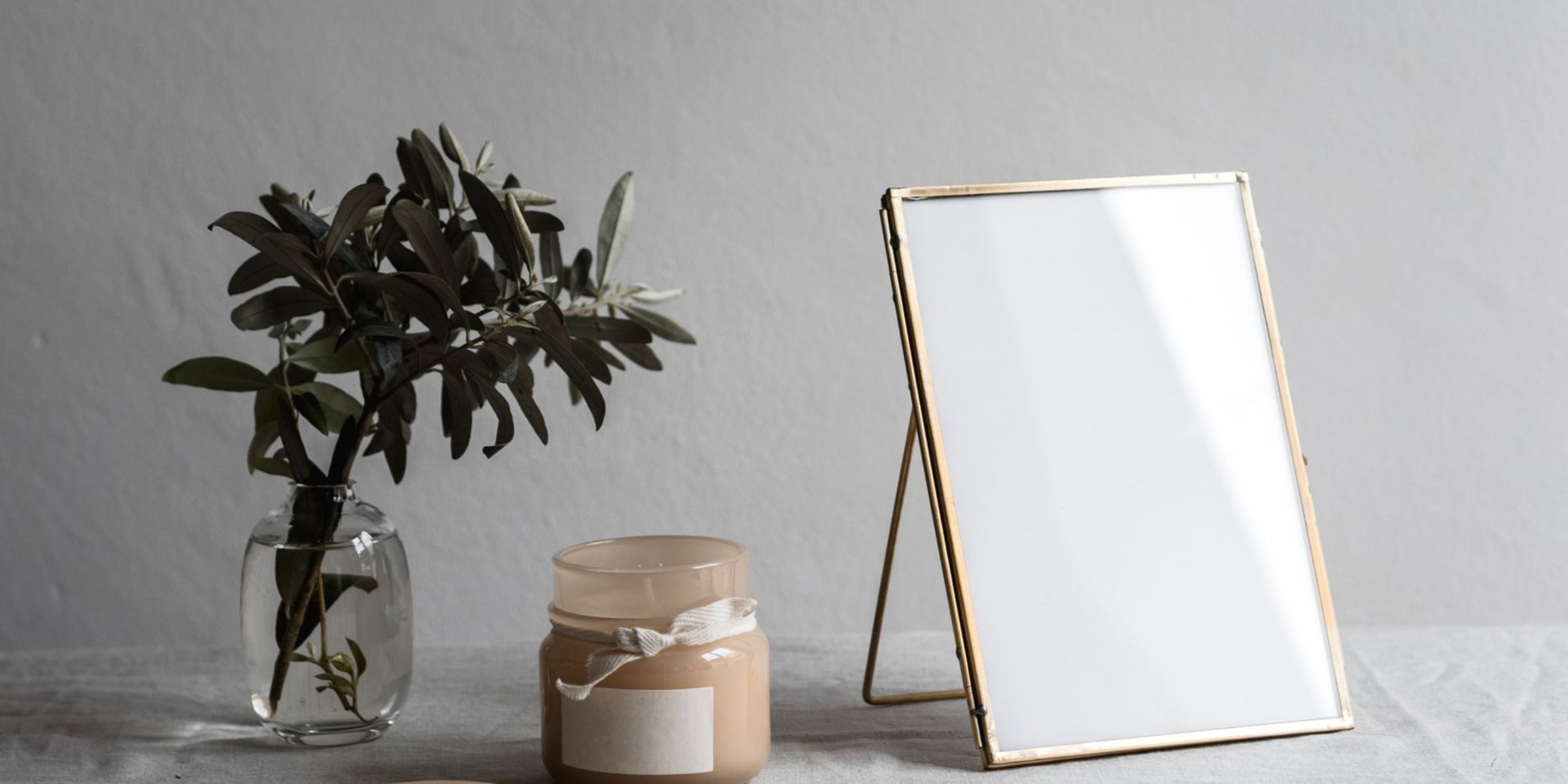 A framed photograph sitting beside a candle and vase of greenery | Source: Pexels
