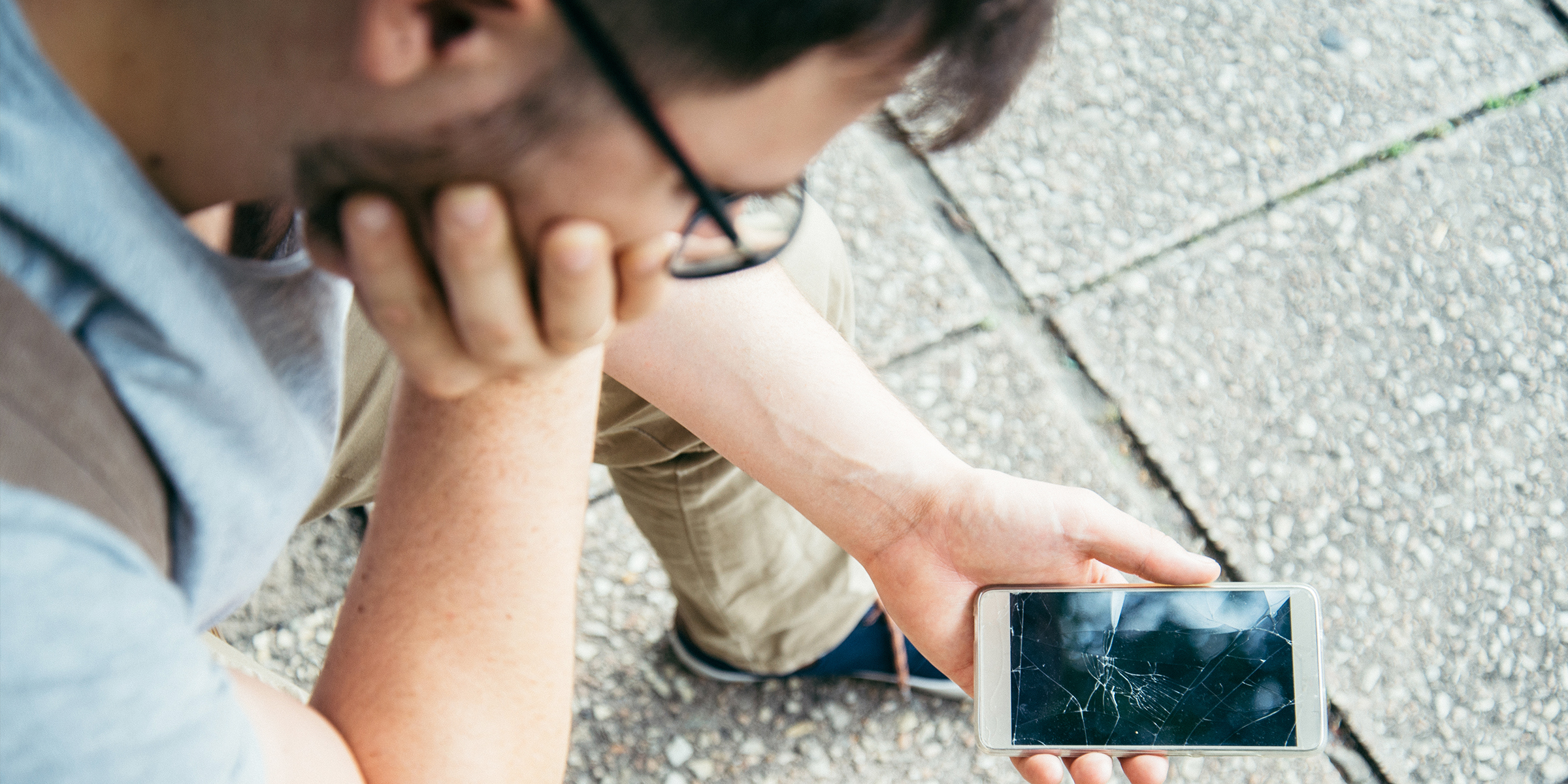 A man looking at a broken phone | Source: Shutterstock