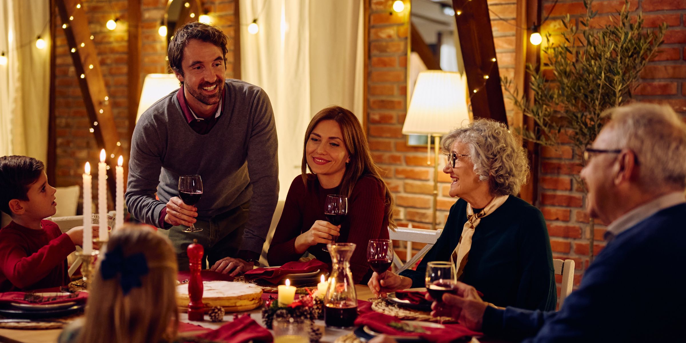 A family gathered around the dinner table for a celebratory meal and toast. | Source: Shutterstock